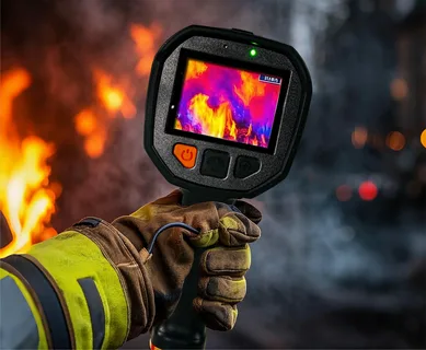 Licensed electrician using a thermal imaging camera to inspect a commercial electrical switchboard in New Zealand.